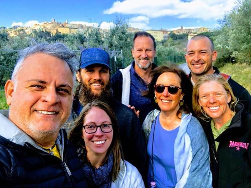 Group selfie of smiling friends with a hill town in the background