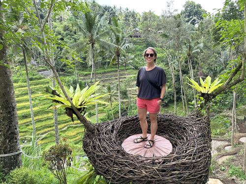 Allie standing in a giant bird’s nest above terraced rice fields