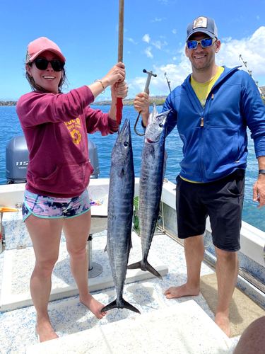 Two people on a boat holding up their catch