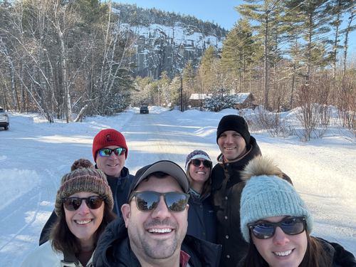 Four friends in winter hats taking a selfie in the snow