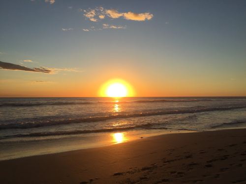 The sun setting over the ocean from a beach