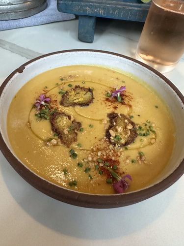 A bowl of golden soup garnished with flowers