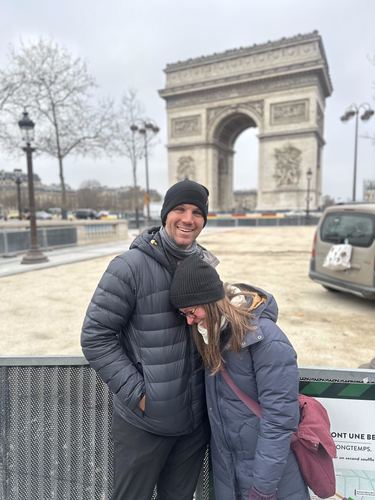 A couple in winter coats in front of the Arc de Triomphe