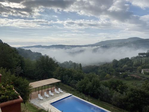 Low clouds over green hills above a swimming pool