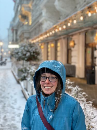 A woman in a blue hooded jacket on a snowy street