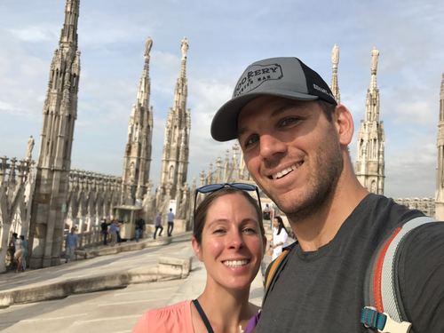 Allie and Chase smiling in front of the spires of a cathedral