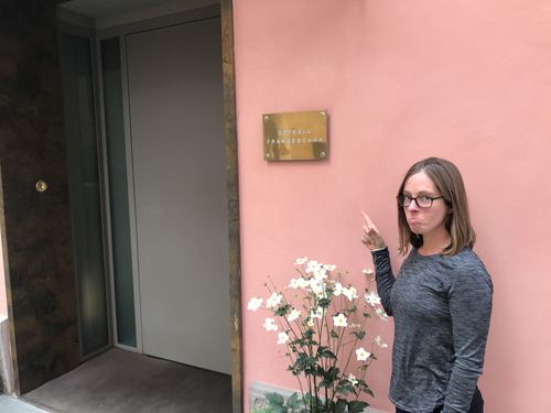 Allie pointing at a plaque on a pink wall