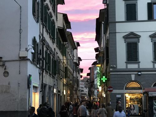 A busy street at dusk under a pink sky