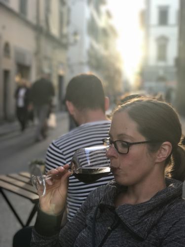 A woman sipping red wine at a café table