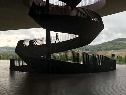 A black spiral staircase in a modern building above rolling hills