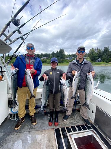 Three men on a boat holding up their fish