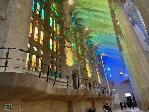 Colored light from the stained glass spilling across the walls inside La Sagrada Familia